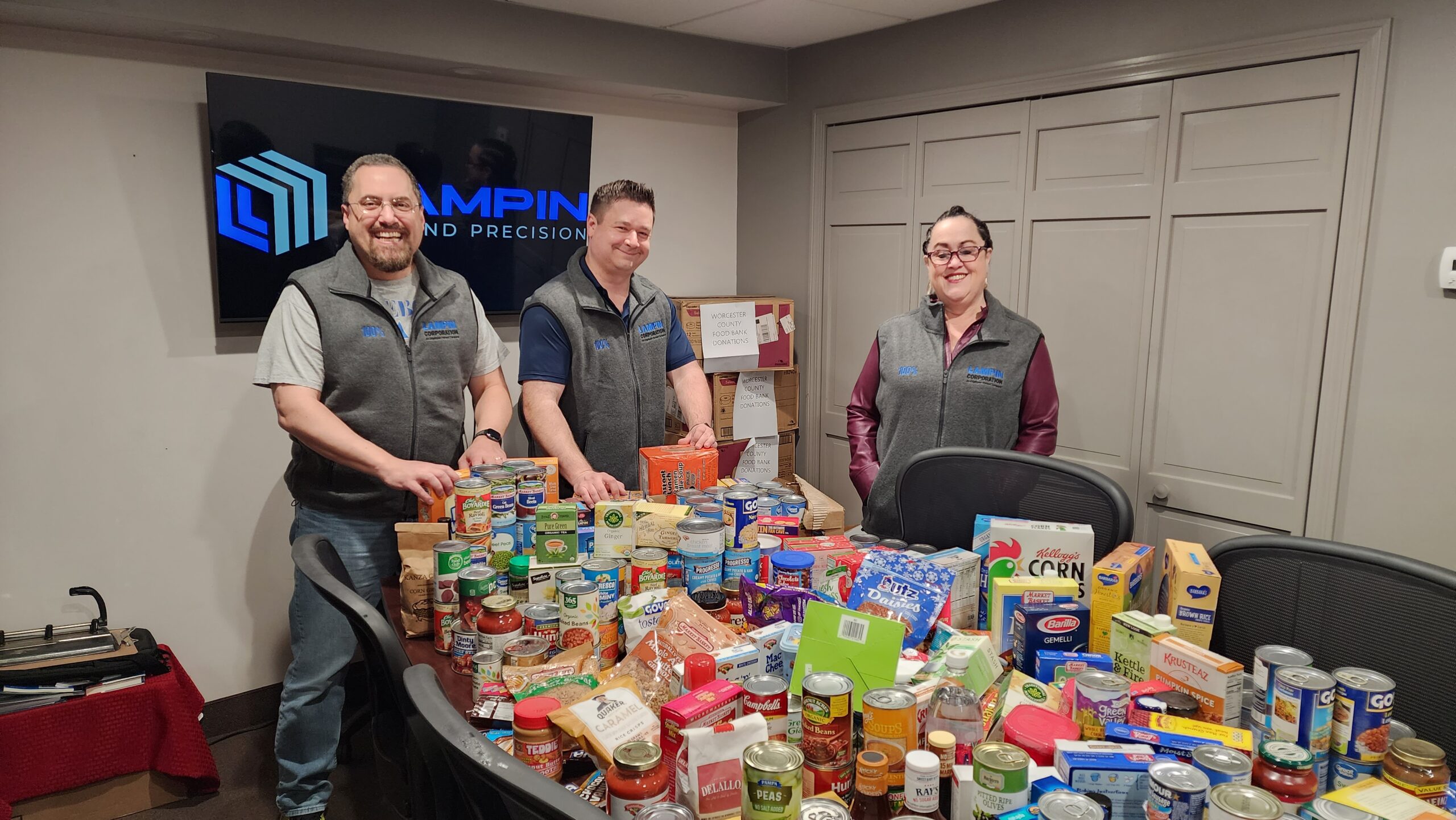 Lampin employee owners stand behind a table covered in food donations