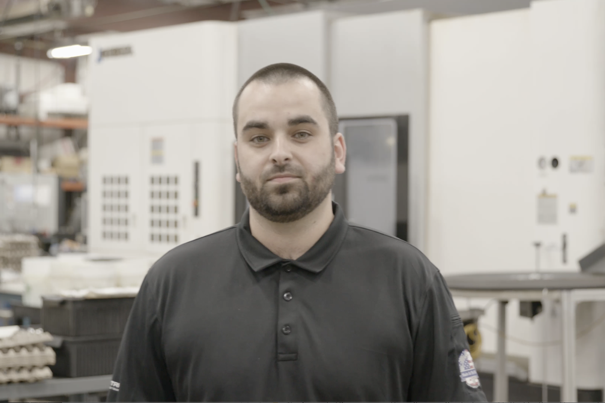 Erik monitors a complex machining setup on the shop floor at Lampin, demonstrating the technical expertise gained through the company’s mentorship program.